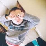 Boy covering his eyes with his hands.