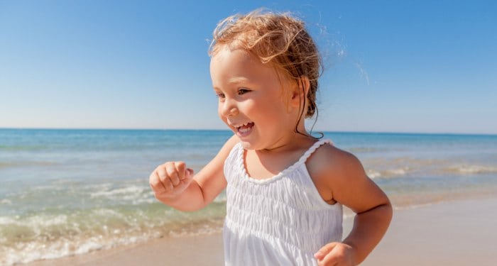 young toddler girl running and smiling on the beach