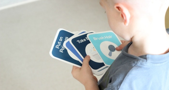 Child holding bedtime routine cards in hand.