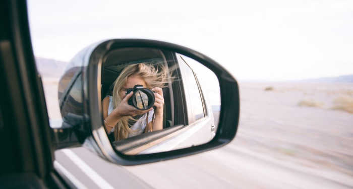 A woman hanging out the side view mirror of a car