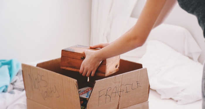woman placing small wooden box into moving box
