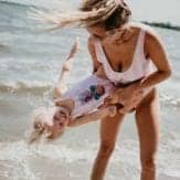 mom in swimsuit spinning toddler near ocean