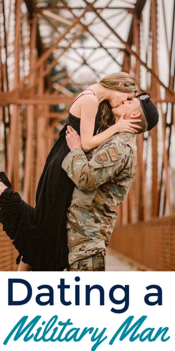 Military man and girlfriend kissing on a bridge.
