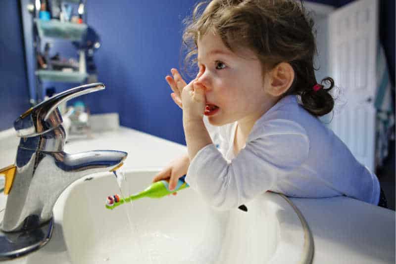 Child brushing her teeth in the morning. 