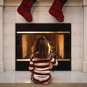 toddler girl waiting by the fire with stockings hung