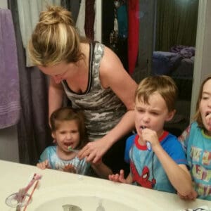 Mom helping kids brush teeth
