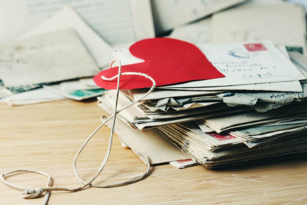 stack of written letters with cut out red paper heart on top
